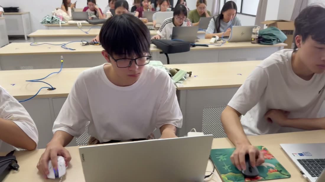 教室里学生并排使用笔记本电脑